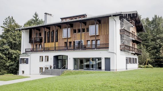 Außenansicht der Jugendherberge Berchtesgaden, das modernisierte Haus Untersberg. Mit Holz verkleidet von außen und großen Fenstern.