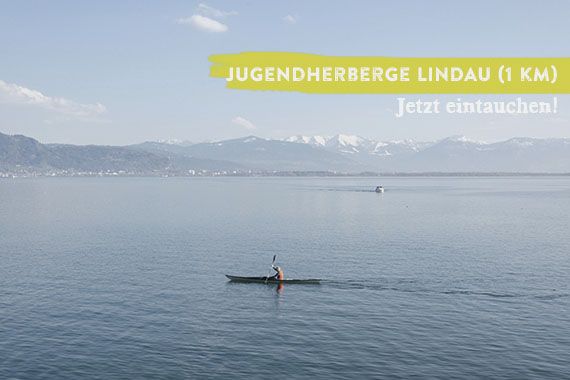 Weiter Block über den Bodensee. Im Zentrum des Fotos ein Kajak auf dem See. Das Bild wird überlagert vom Schriftzug "Jugendherberge Lindau - jetzt eintauchen".