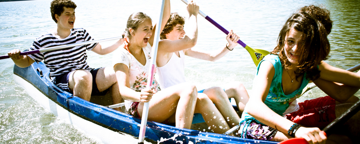 Mehrere Kinder haben viel Spaß in einem kleinen Boot auf einem See 